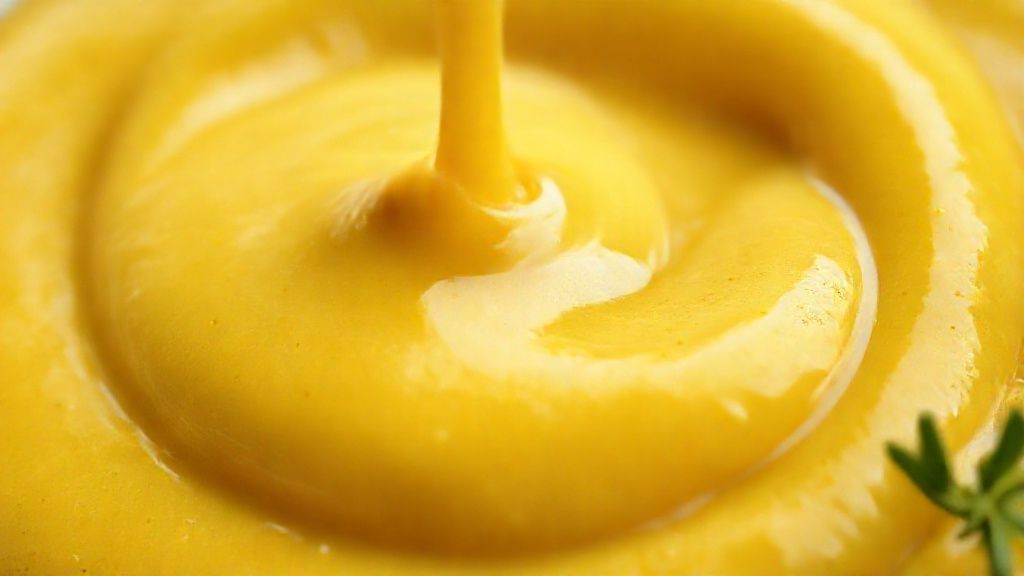 Close-up do molho de mostarda e mel mostrando a textura cremosa e cor dourada.