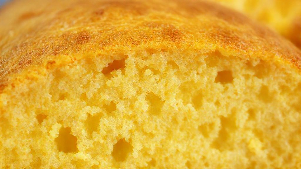 Close-up do pão recém-assado, mostrando miolo fofo e crosta dourada com leve brilho.