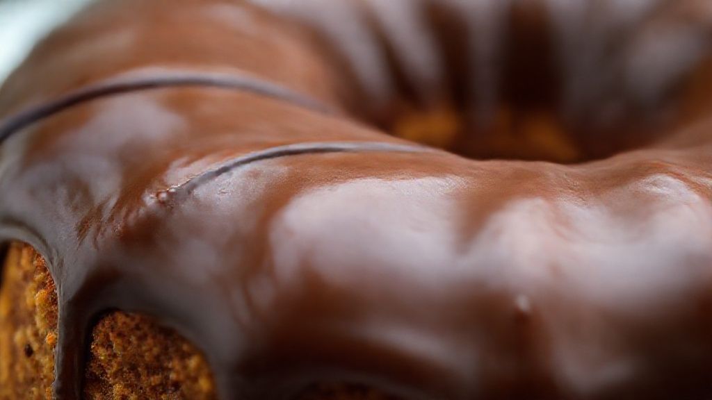 Close-up do pão de mel cortado, com cobertura de chocolate brilhante e textura úmida