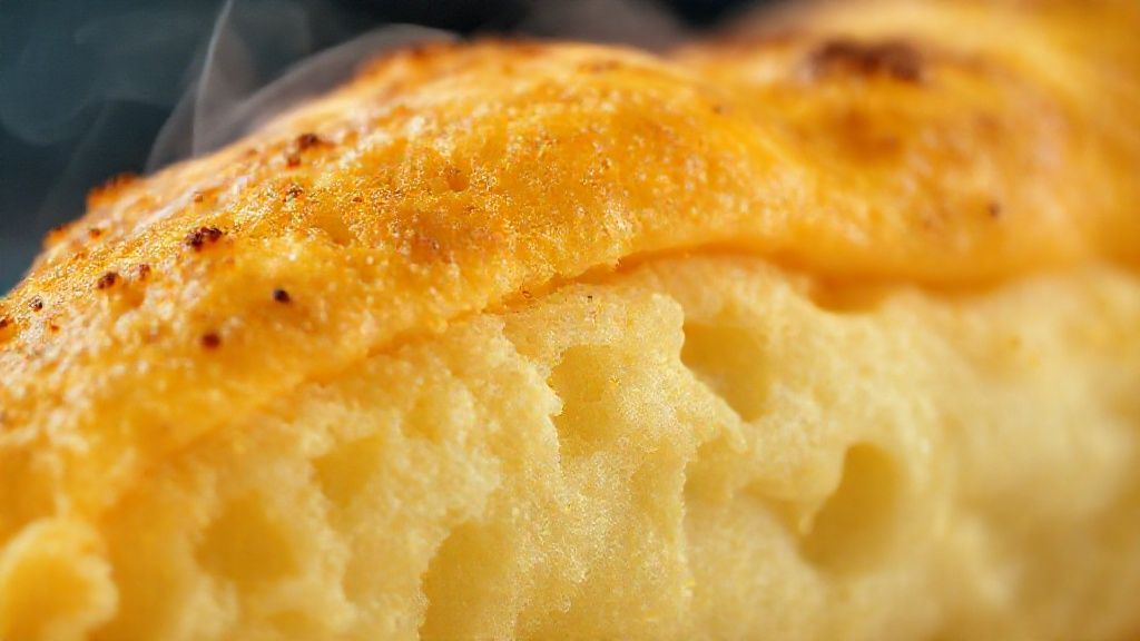 Close-up do pastel aberto mostrando recheio suculento e massa crocante