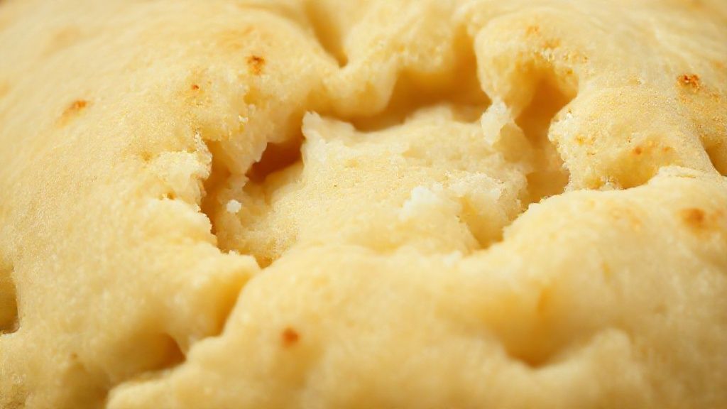 Close-up mostrando o interior macio e dourado do salgado assado recém-saído do forno