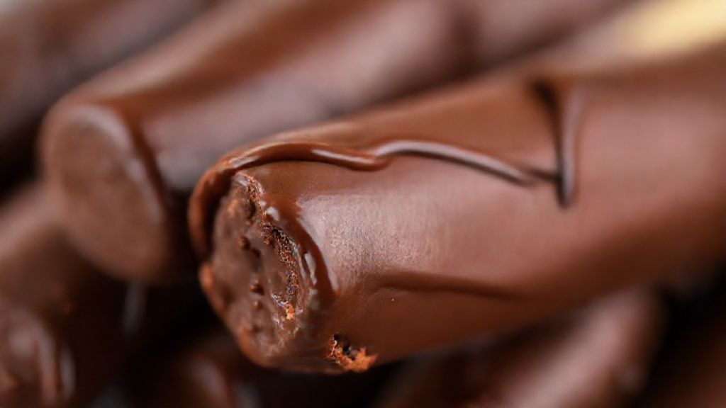 Close-up dos palitinhos banhados em chocolate, destacando o contraste da textura crocante