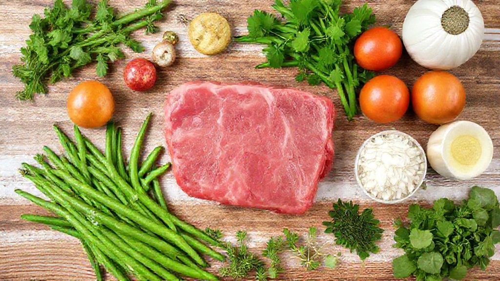 Visão superior dos ingredientes — tiras de carne, vagens cortadas, cebola, alho e temperos dispostos sobre bancada de madeira