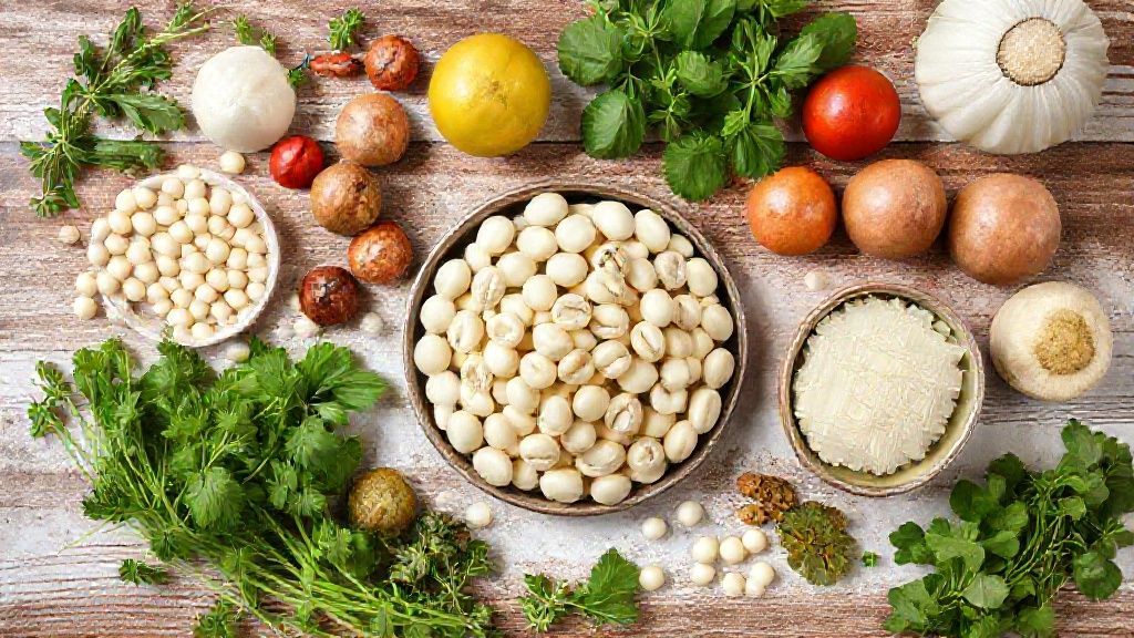 Visão de cima com feijão cru, alho, cebola, louro e temperos organizados em bancada de madeira