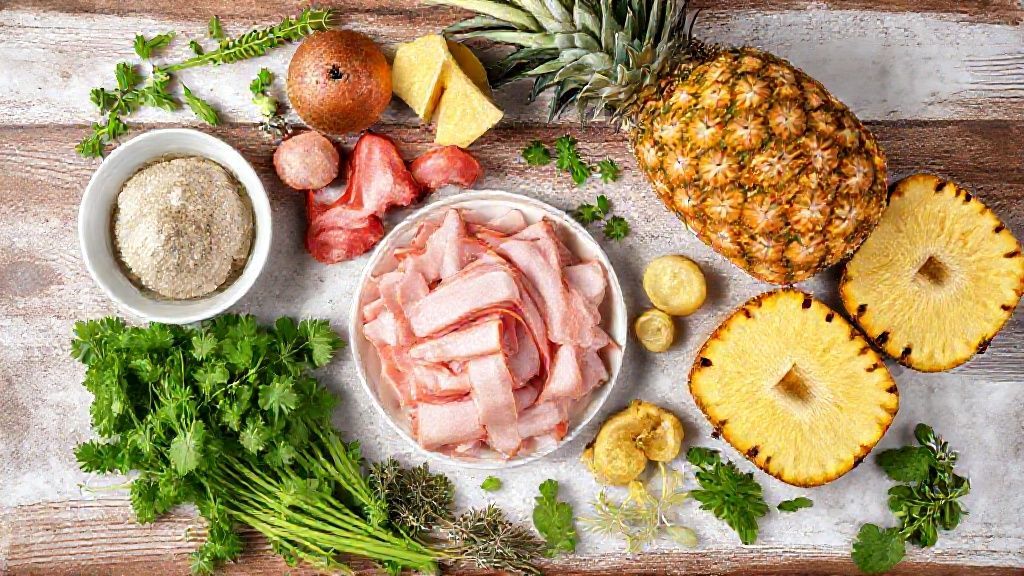 Ingredientes organizados sobre bancada: farinha de mandioca, bacon, calabresa, abacaxi e temperos frescos