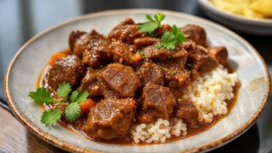 Prato de picadinho de carne servido com arroz branco e farofa, com molho rico e legumes no ponto certo