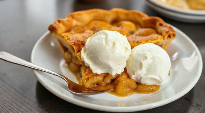 Torta de maçã dourada, servida morna com sorvete de creme derretendo, apresentando contraste de texturas e aromas.