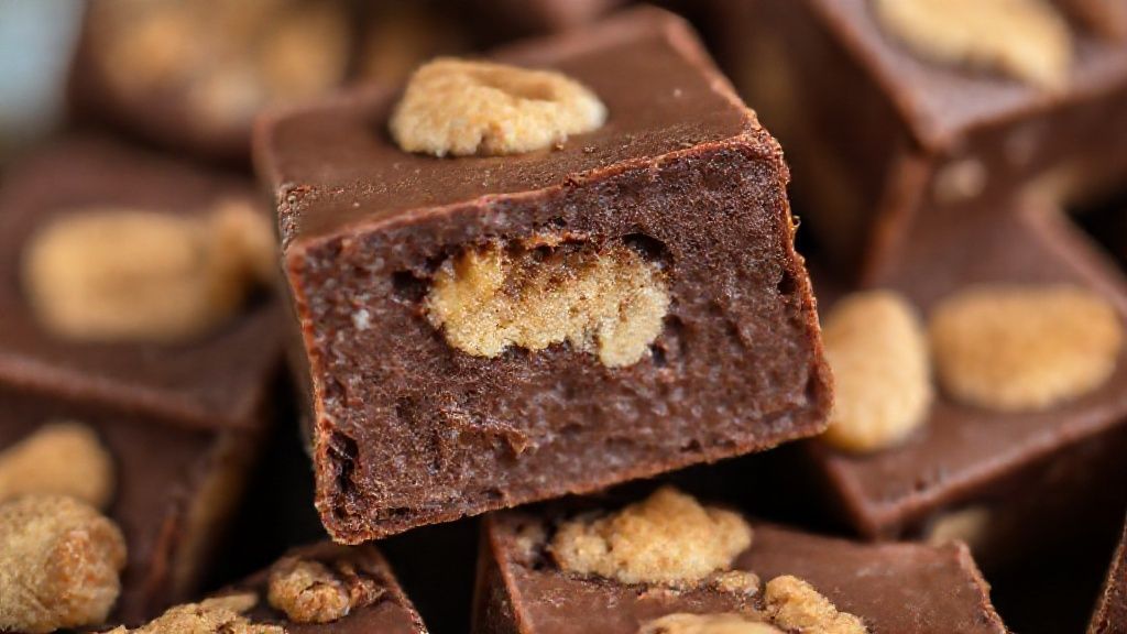 Close-up mostrando textura cremosa e os pedaços de biscoito no doce cortado em quadradinhos