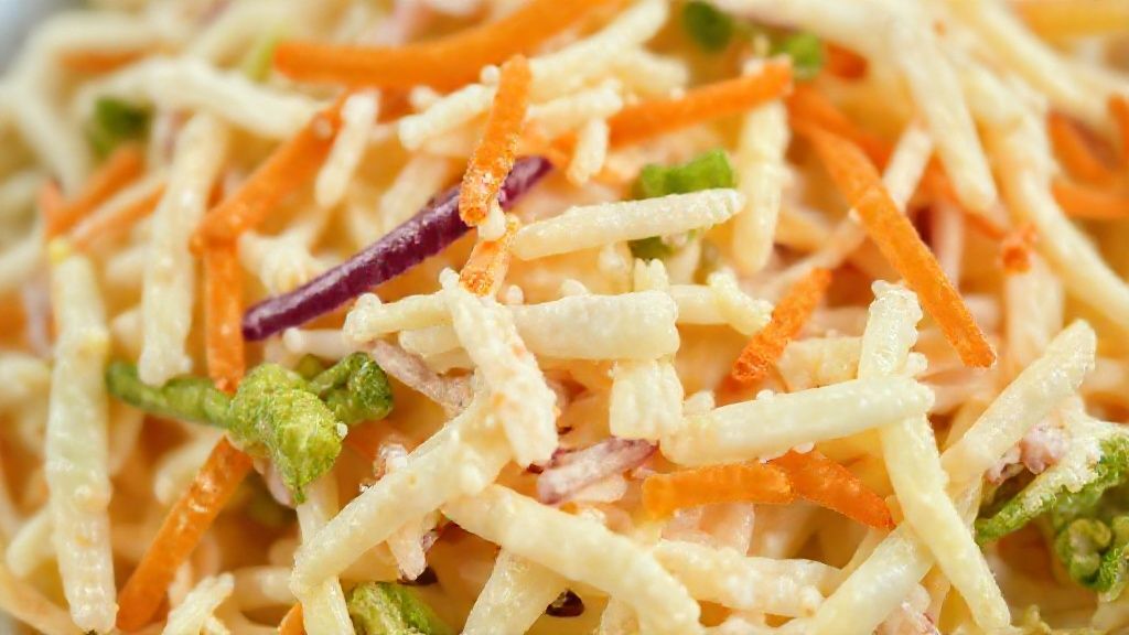 Close-up da textura cremosa e colorida da salada de repolho, destacando o frescor dos ingredientes