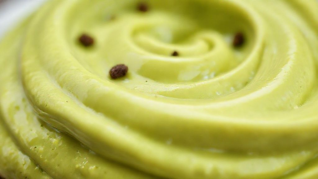 Close-up da sobremesa de abacate cremosa em taça, mostrando textura suave e brilho da superfície.