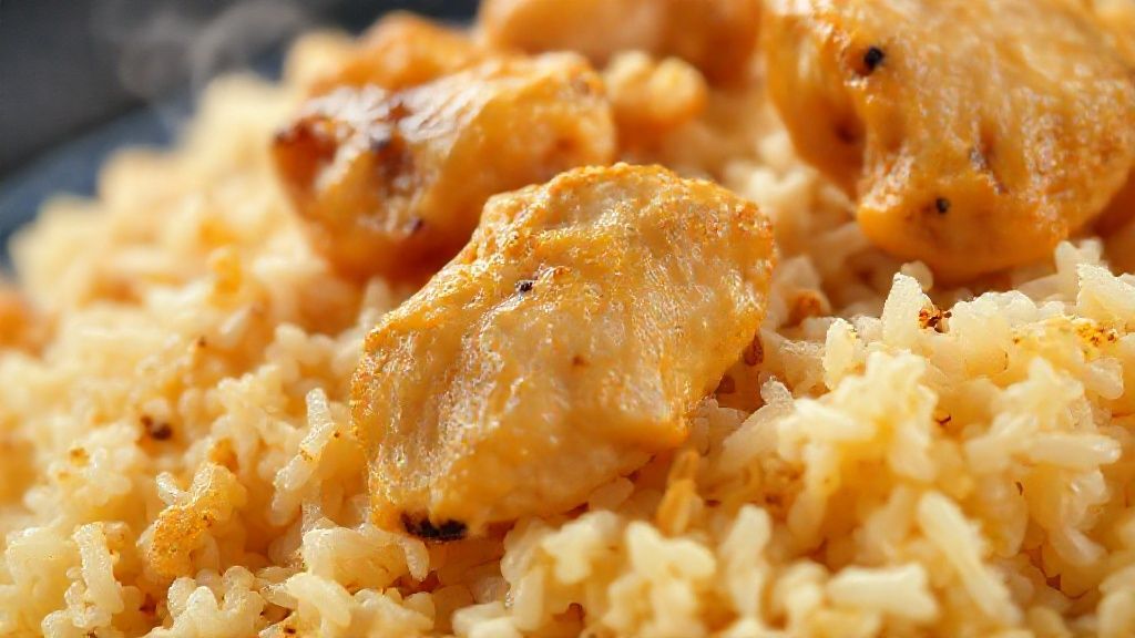 Close-up do arroz com frango pronto, destacando o brilho do frango dourado e o arroz soltinho