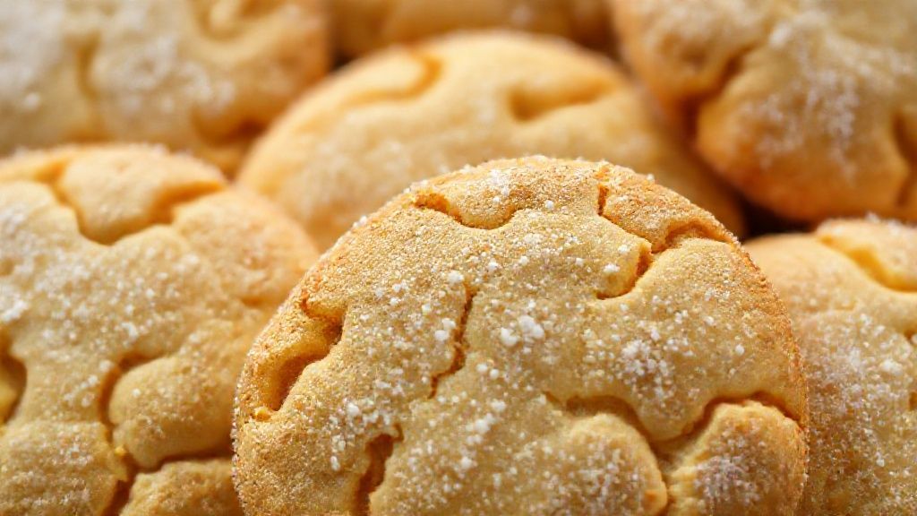 Close-up dos biscoitinhos caipiras dourados e crocantes, com textura destacada e leve pó de açúcar