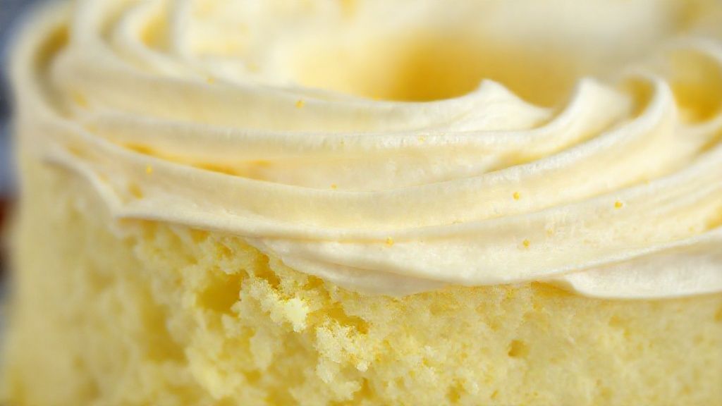 Close-up da fatia de bolo de limão fofinho mostrando sua textura úmida e cobertura brilhante.