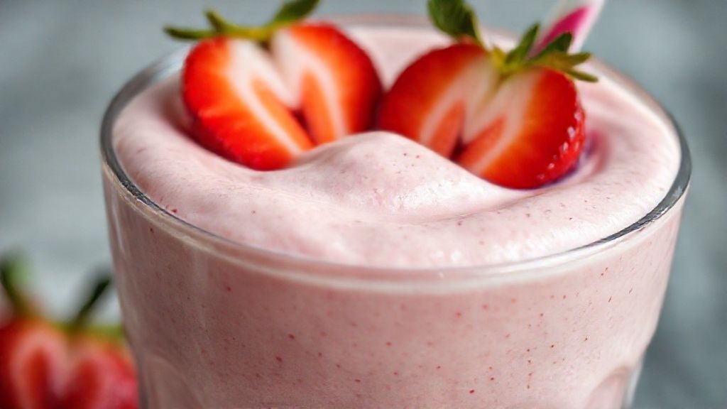 Close-up do smoothie mostrando textura cremosa e cor vibrante, com morangos fatiados