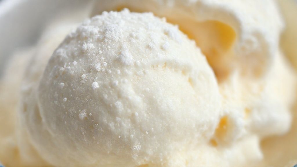 Close-up do sorvete finalizado, destacando a textura cremosa e o brilho do leite em pó por cima