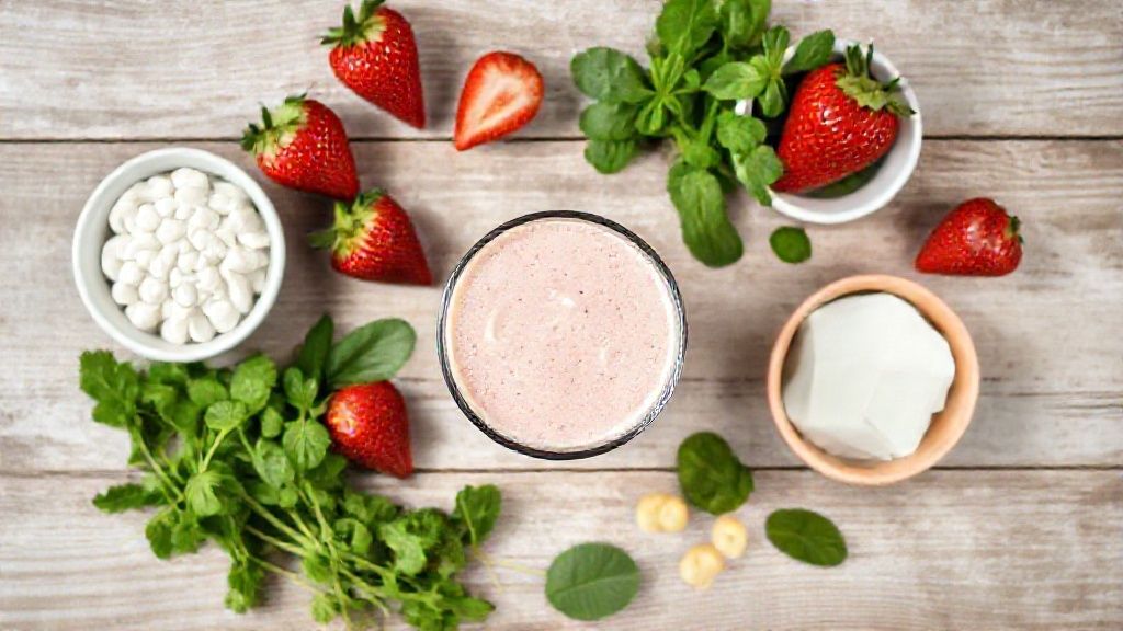 Ingredientes frescos organizados na bancada: morangos, iogurte, banana, mel e leite