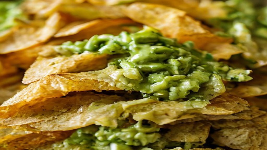 Close-up mostrando a textura crocante dos chips e a cremosidade do guacamole