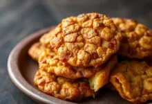 Bolinhos dourados e crocantes de feijão-fradinho, com casca estaladiça e interior macio, servidos em um prato de barro rústico.