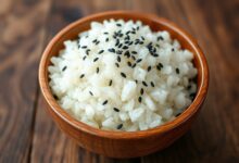 Tigela de madeira com arroz de sushi brilhante, grãos perfeitamente soltos e levemente pegajosos.