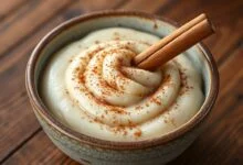 Uma travessa de arroz doce cremoso, polvilhado generosamente com canela em pó e decorado com canela em pau, pronto para servir.