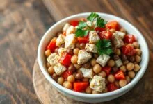 Salada vibrante e colorida, com bacalhau desfiado, feijões-fradinho inteiros, cubos de tomate e pimentão vermelho, finalizada com folhas de salsinha fresca.