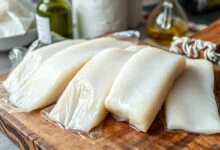 Pedaços de bacalhau branco e firme, pincelados com azeite e embalados individualmente, prontos para o freezer.