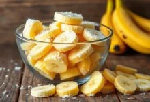 Bowl de vidro transbordando de rodelas de banana congelada, prontas para uso.