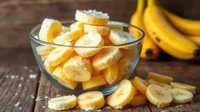 Bowl de vidro transbordando de rodelas de banana congelada, prontas para uso.