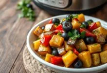 Cubos de berinjela dourados e firmes, salpicados com azeitonas fatiadas e cheiro-verde fresco, prontos para servir.