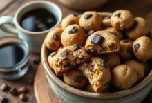 Uma tigela de cerâmica rústica transbordando de biscoitinhos de café dourados, com pedaços visíveis de chocolate derretido e amendoim torrado.