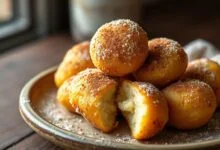 Bolinhos de chuva dourados e fofinhos, polvilhados com açúcar e canela, prontos para servir