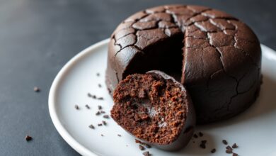 Bolo de brigadeiro inteiro, com superfície craquelada e cor marrom escuro, fatiado para revelar o interior úmido e fofinho.