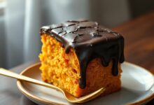 Bolo de cenoura alto com cobertura de chocolate que brilha e apresenta rachaduras crocantes