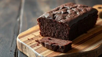 Um bolo de chocolate escuro, fofinho e úmido, fatiado para revelar a textura macia, em uma superfície rústica de madeira.