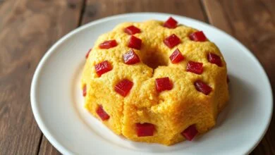 Bolo de fubá dourado com pedaços de goiabada vermelha visíveis, fatiado e pronto para servir.
