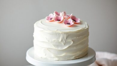 Um bolo redondo perfeitamente coberto com uma pasta de marshmallow branca e lisa, com textura firme e acabamento profissional.