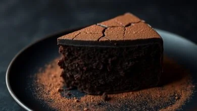 Fatia generosa de bolo negro de chocolate com textura densa e úmida