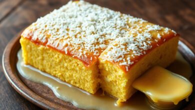 O bolo de fubá finalizado, com sua superfície encharcada e macia, coberta por flocos de coco, fatiado e pronto para servir.