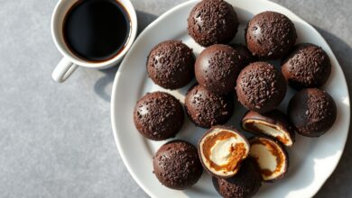 Vista de cima de vários brigadeiros de café perfeitamente enrolados e cobertos com granulado de chocolate amargo, servidos em um prato de porcelana branca.