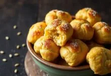 Broas douradas e macias, com a casca levemente rachada e um aroma intenso de erva-doce, servidas em uma travessa de barro.