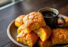 Broas de fubá douradas e perfeitas, com a casca craquelada e o interior macio à mostra, prontas para servir.