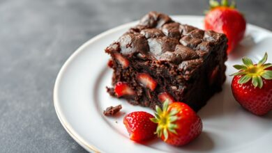 Fatias de brownie de morango com textura densa, casquinha craquelada e pedaços de morango vermelho visíveis.