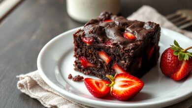 Fatia generosa de brownie denso com pedaços de morango caramelizado, centro úmido e cobertura brilhante de chocolate.