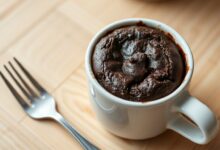 Brownie individual úmido e intenso servido direto na caneca, com textura macia e crosta leve por cima.