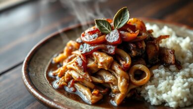Pedaços de carne de porco dourada e suculenta, desfiada e coberta por um molho rico, servida em um prato rústico com cebolas e louro.