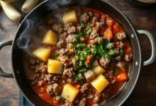 Uma panela larga com carne moída marrom dourada e cubos de chuchu macio e translúcido, finalizada com salsinha fresca, pronta para servir.