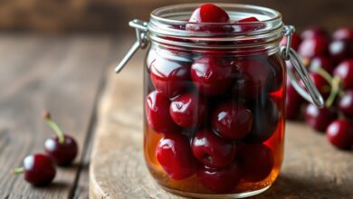 Pote de vidro com cerejas vermelhas brilhantes e firmes em uma calda espessa e translúcida, pronto para ser servido.