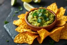 Chips dourados e crocantes ao redor de guacamole cremoso, prato perfeito para happy hour.