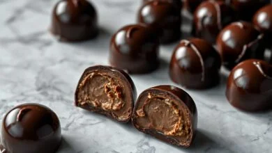 Bombons de chocolate escuro com superfície brilhante, lisa e sem manchas brancas, demonstrando o resultado ideal da temperagem.
