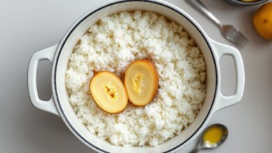 Como Tirar O Sal Do Arroz: 4 Técnicas Rápidas Que Funcionam 9 Panela de arroz branco com uma batata crua cortada ao meio dentro, demonstrando o truque para corrigir o sal